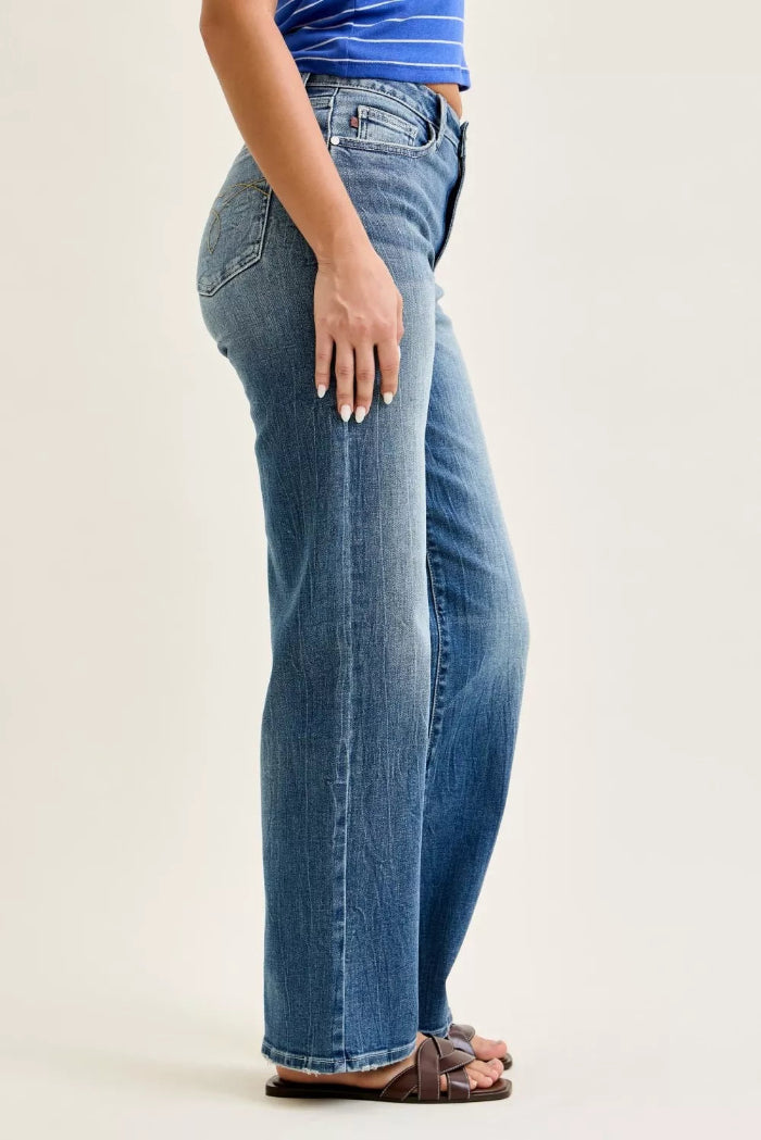 Person wearing blue jeans and a striped shirt on a plain background