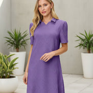 Woman wearing a purple dress with a collar on a beige background