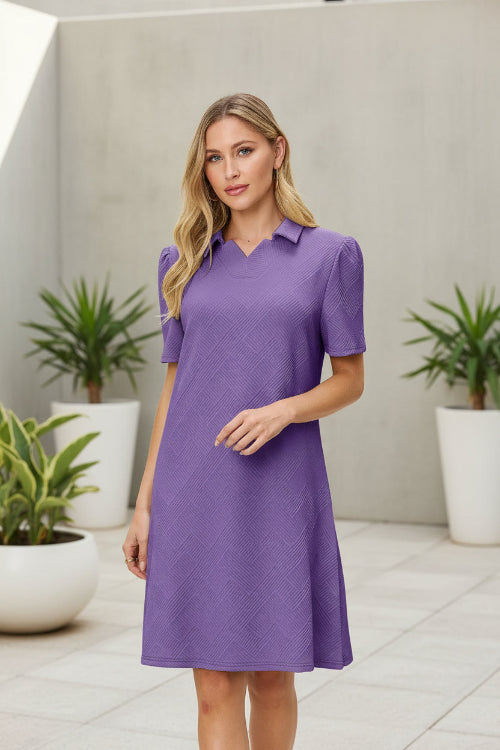 Woman wearing a purple dress with a collar on a beige background