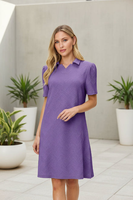 Woman wearing a purple dress with a collar on a beige background
