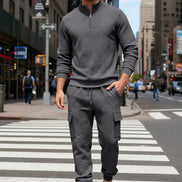 A man wearing a dark gray textured quarter-zip pullover and matching cargo jogger pants 