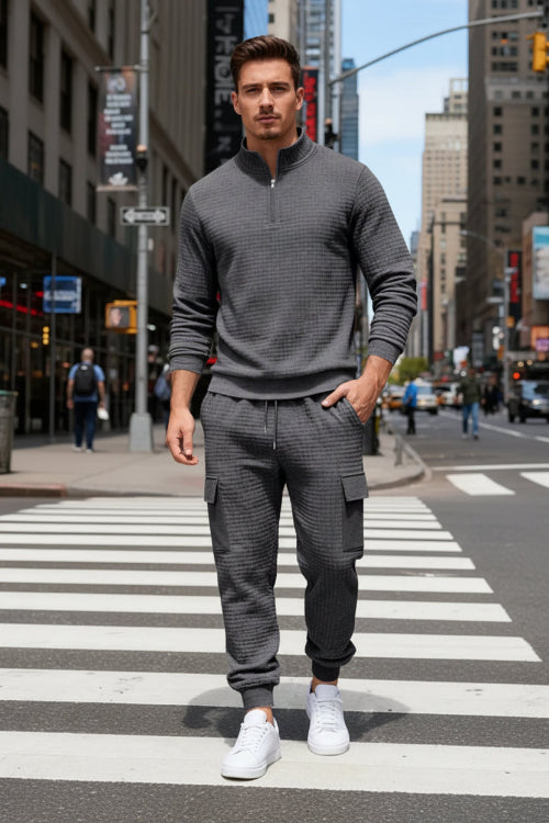 A man wearing a dark gray textured quarter-zip pullover and matching cargo jogger pants 