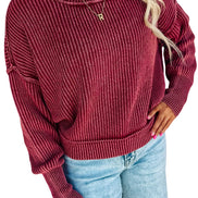 A woman wearing a ribbed knit long-sleeve sweater in a deep burgundy red, paired with light blue jeans, 